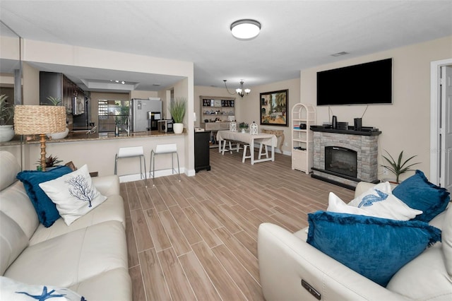 living room with a fireplace, an inviting chandelier, and wood tiled floor