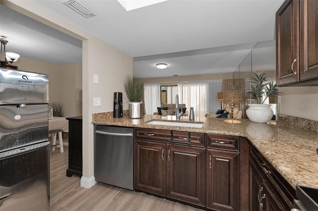 kitchen featuring dark brown cabinets, visible vents, stainless steel appliances, and a sink