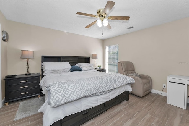 bedroom featuring baseboards, visible vents, ceiling fan, wood tiled floor, and a textured ceiling