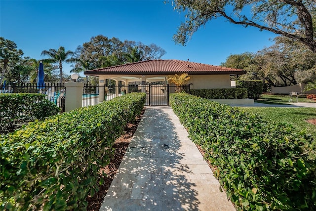 view of front of home with a gate, a tile roof, fence, and stucco siding