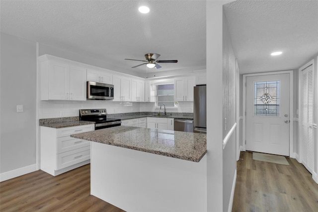 kitchen featuring sink, light hardwood / wood-style flooring, stainless steel appliances, light stone countertops, and white cabinets