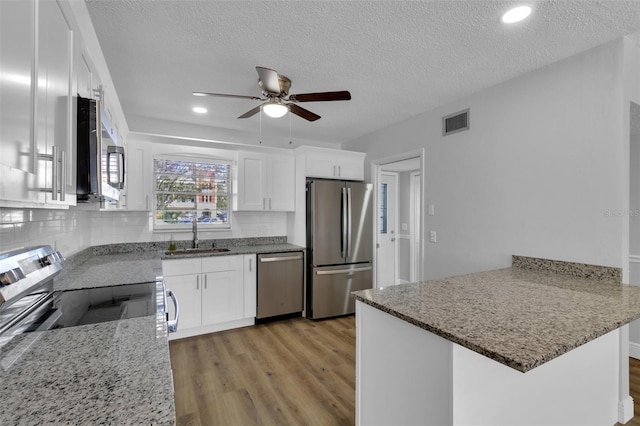 kitchen with sink, white cabinets, kitchen peninsula, stainless steel appliances, and light hardwood / wood-style flooring