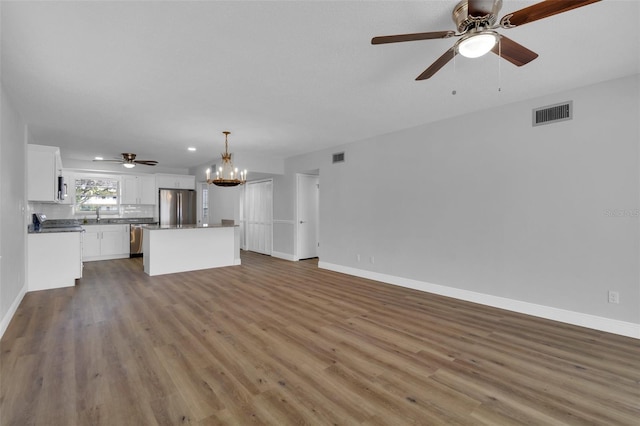 unfurnished living room with hardwood / wood-style floors, ceiling fan with notable chandelier, and sink