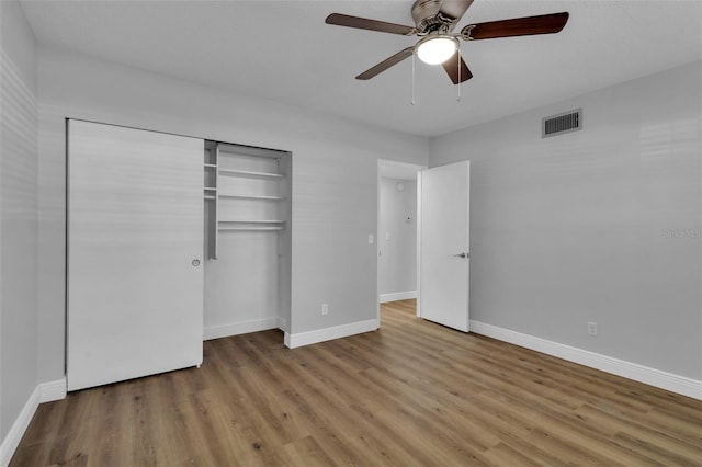 unfurnished bedroom featuring hardwood / wood-style flooring, ceiling fan, and a closet