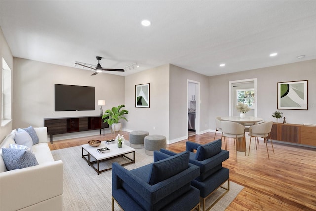 living room with ceiling fan, track lighting, and light hardwood / wood-style flooring