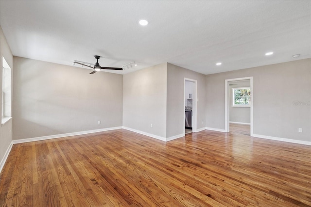 empty room with hardwood / wood-style flooring, rail lighting, and ceiling fan