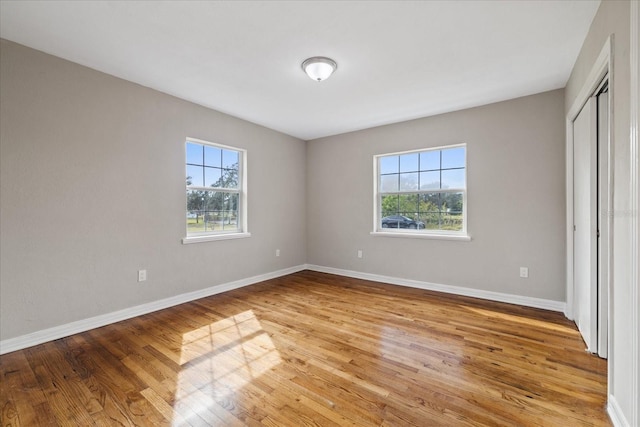 unfurnished bedroom featuring a closet, multiple windows, and light hardwood / wood-style flooring