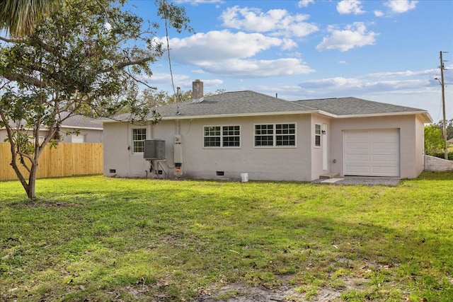 rear view of property featuring a garage and a lawn