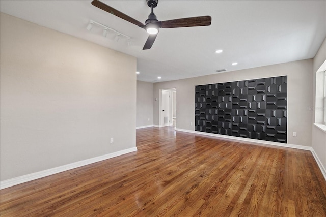 unfurnished living room featuring rail lighting, hardwood / wood-style floors, and ceiling fan