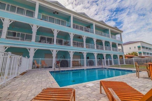 rear view of property with a community pool and a patio area