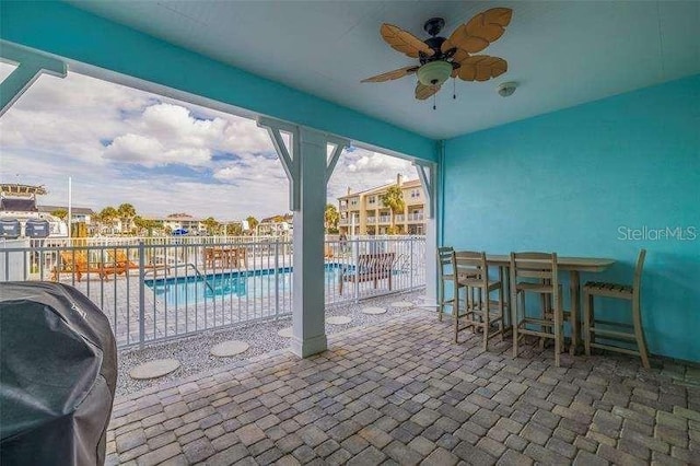 view of patio featuring a grill, a community pool, an outdoor bar, and ceiling fan