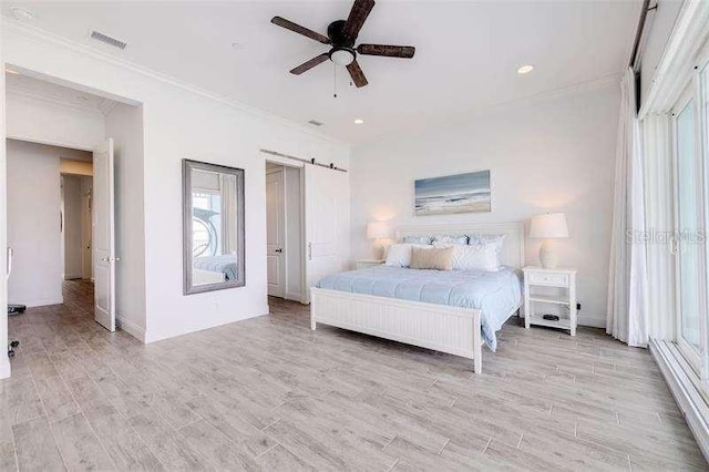 bedroom with ornamental molding, a barn door, ceiling fan, and light hardwood / wood-style flooring