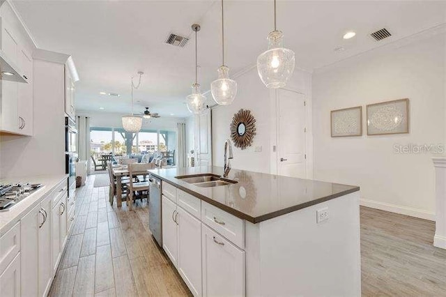 kitchen featuring pendant lighting, sink, a center island with sink, and white cabinets