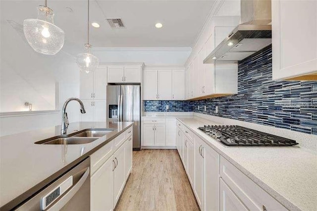 kitchen featuring wall chimney exhaust hood, sink, white cabinetry, hanging light fixtures, and appliances with stainless steel finishes