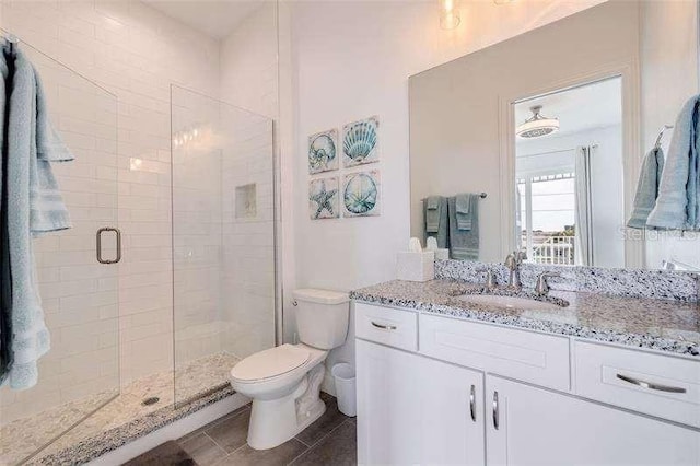 full bath featuring tile patterned flooring, a shower stall, toilet, and vanity