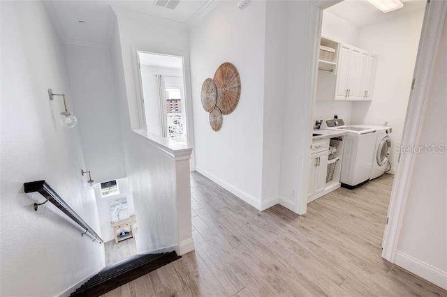 hall featuring light wood finished floors, visible vents, crown molding, and baseboards