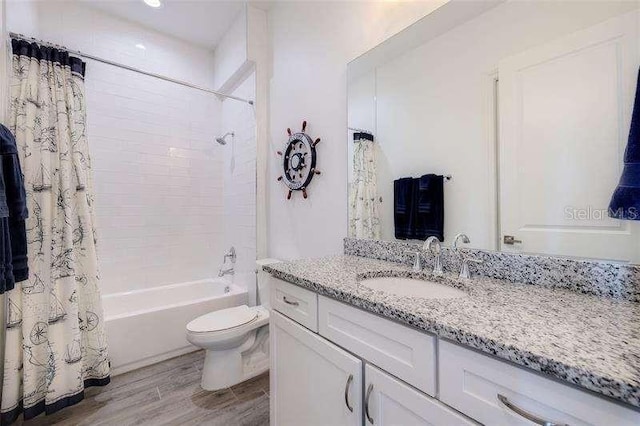 bathroom with vanity, toilet, wood finished floors, and shower / bath combo with shower curtain