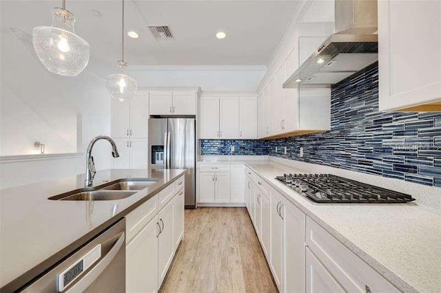 kitchen with visible vents, a sink, hanging light fixtures, appliances with stainless steel finishes, and wall chimney exhaust hood