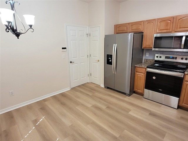 kitchen with stainless steel appliances, a chandelier, and light hardwood / wood-style floors