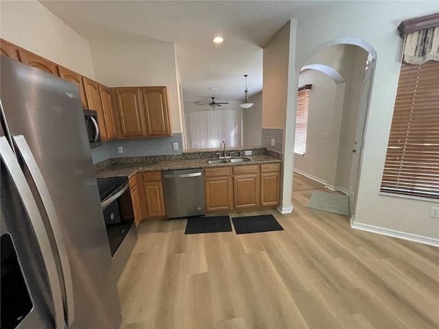 kitchen with sink, decorative backsplash, hanging light fixtures, stainless steel appliances, and light wood-type flooring