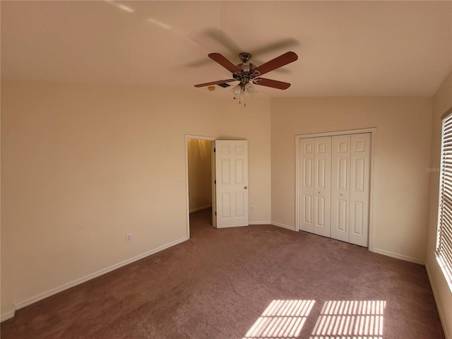 unfurnished bedroom featuring ceiling fan, lofted ceiling, a closet, and dark colored carpet