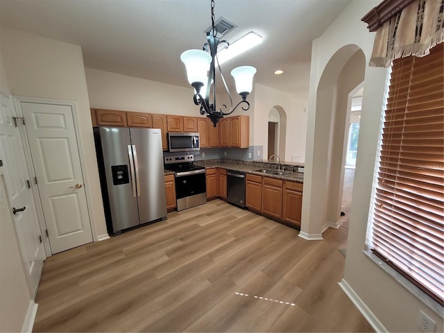 kitchen featuring pendant lighting, sink, stainless steel appliances, a chandelier, and light wood-type flooring