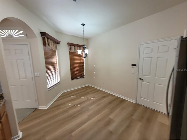 unfurnished dining area with hardwood / wood-style flooring and a notable chandelier