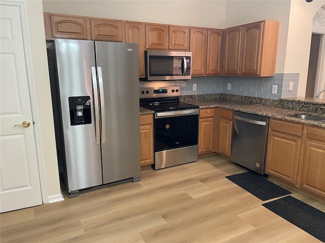 kitchen featuring tasteful backsplash, stainless steel appliances, light hardwood / wood-style floors, and sink