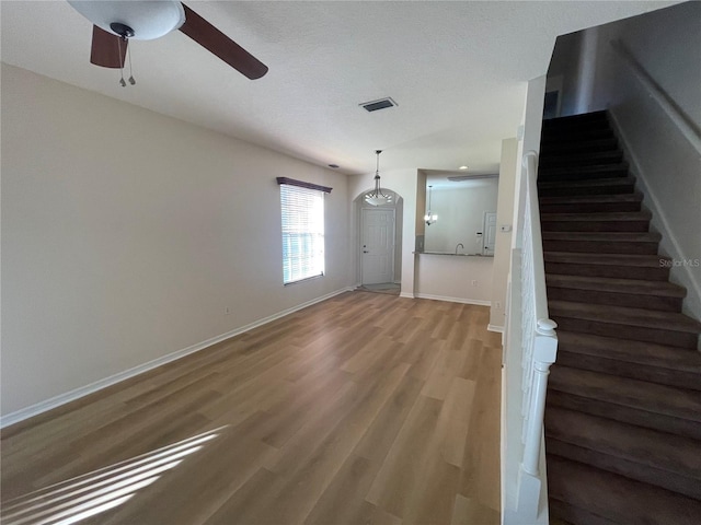 stairway with ceiling fan and hardwood / wood-style floors