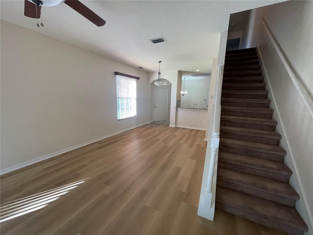 staircase featuring ceiling fan and hardwood / wood-style floors