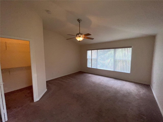 spare room featuring ceiling fan, vaulted ceiling, and dark colored carpet