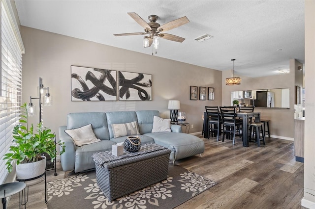 living room with ceiling fan, a textured ceiling, and dark hardwood / wood-style flooring