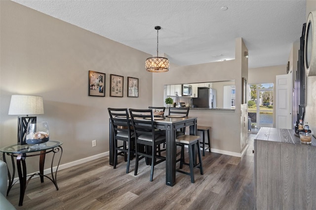 dining space with dark wood-type flooring and a textured ceiling