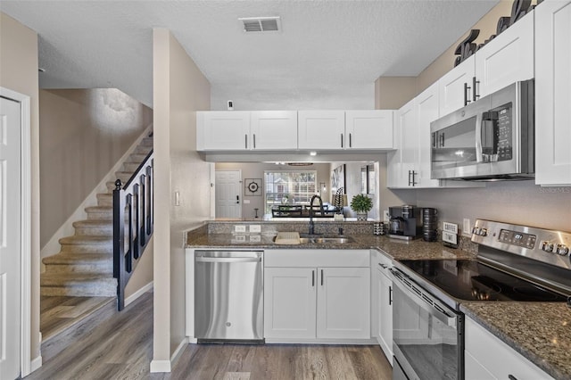 kitchen featuring white cabinetry, appliances with stainless steel finishes, sink, and dark stone countertops