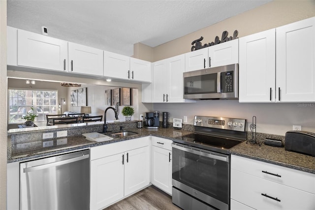 kitchen with white cabinetry, appliances with stainless steel finishes, and dark stone countertops