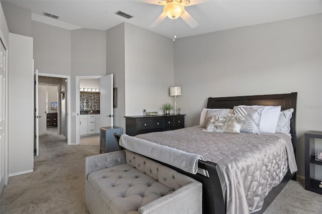 carpeted bedroom with ceiling fan, connected bathroom, and a towering ceiling