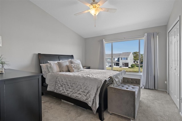 bedroom with lofted ceiling, light colored carpet, ceiling fan, and a closet