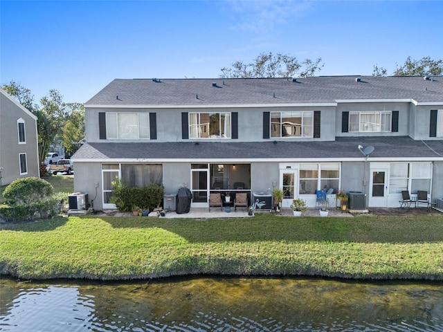 back of house featuring a water view, a yard, and central AC