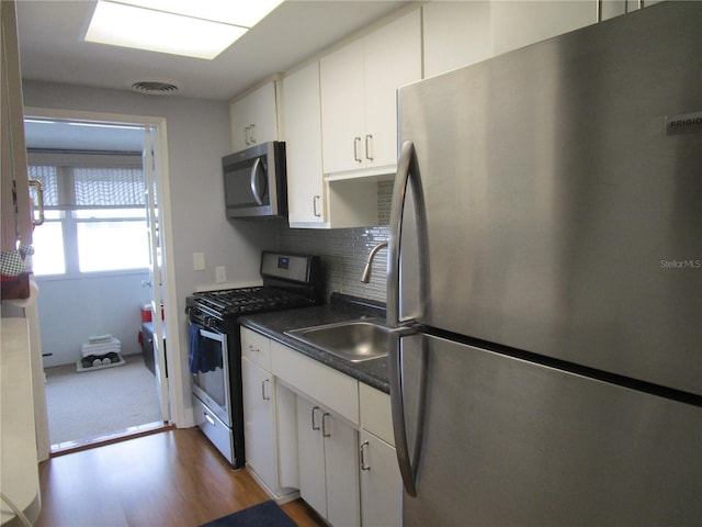 kitchen with sink, tasteful backsplash, appliances with stainless steel finishes, dark hardwood / wood-style floors, and white cabinets