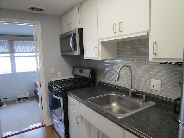 kitchen featuring dark wood-type flooring, sink, white cabinetry, stainless steel appliances, and decorative backsplash