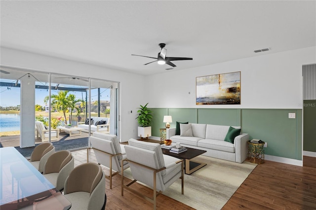 living room with hardwood / wood-style flooring, ceiling fan, and a water view