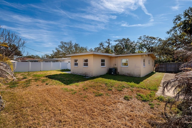 back of property featuring a yard and central AC