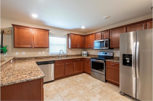 kitchen with light stone countertops, appliances with stainless steel finishes, sink, and light tile patterned floors