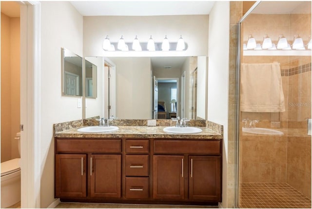 bathroom with vanity, a shower with shower door, and toilet