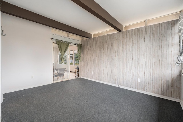 unfurnished room with wooden walls and beam ceiling