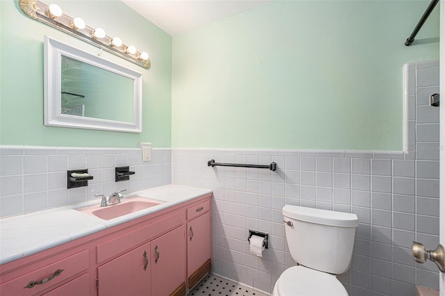 bathroom with vanity, tile walls, and toilet