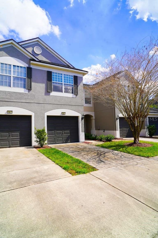 view of front of home featuring a garage, concrete driveway, and stucco siding