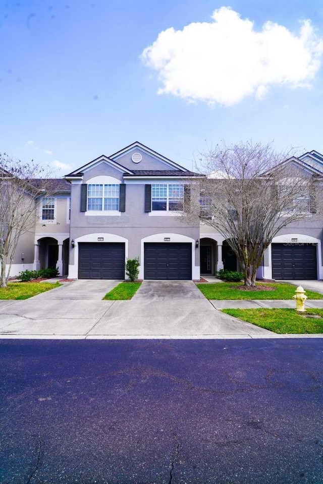 view of front facade with driveway, an attached garage, and stucco siding