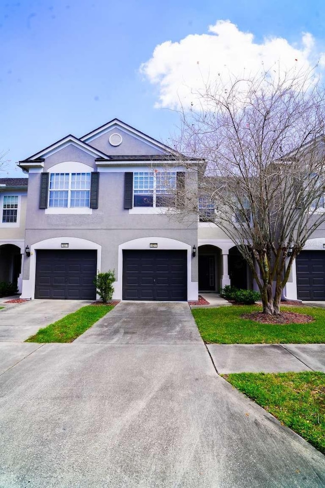 view of front of home with an attached garage, concrete driveway, and stucco siding