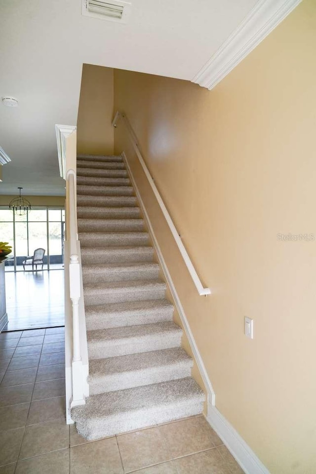 stairway with tile patterned flooring, visible vents, baseboards, and ornamental molding